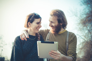 young modern stylish couple using tablet urban