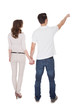 © Andrey Popov - Rear View Of Man Pointing While Holding Woman's Hand