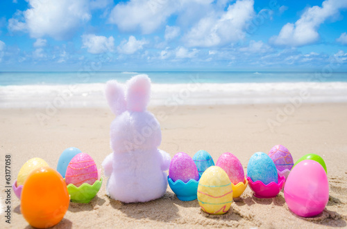 Easter bunny and color eggs on the beach Poster