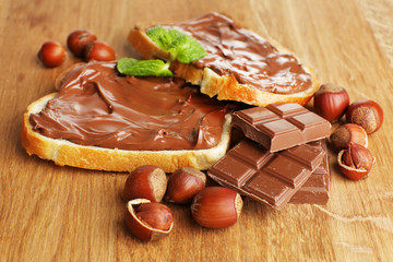 Canvas Print - Bread with sweet chocolate hazelnut spread on wooden background