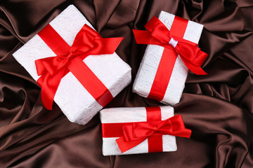 Beautiful gifts with red ribbons on silk background