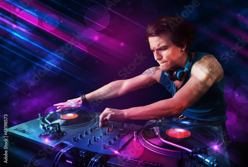 Plakat na papierze fotorealistycznym Młody dj grający na gramofonach z kolorowymi efektami świetlnymi