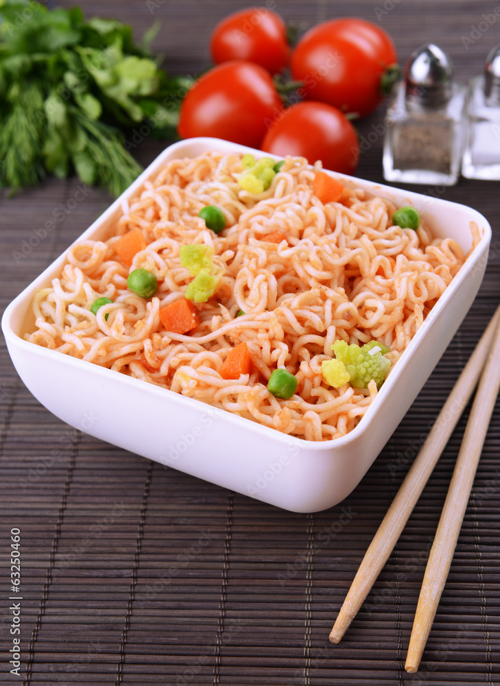 Tasty instant noodles with vegetables in bowl on table close-up