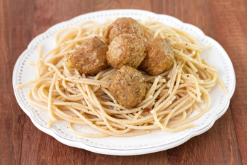 meatballs with spaghetti in plate on brown background