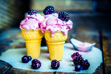 Wall Mural - Ice -cream in cones with berries on rustic wooden background