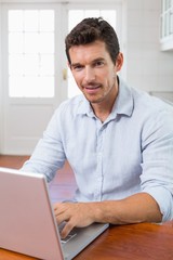 Wall Mural - Smiling young man using laptop