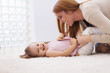 Loving mother tickling her little girl on carpet at home