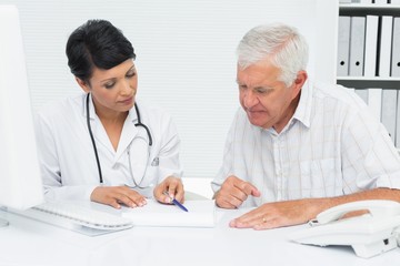 Female doctor with male patient reading reports