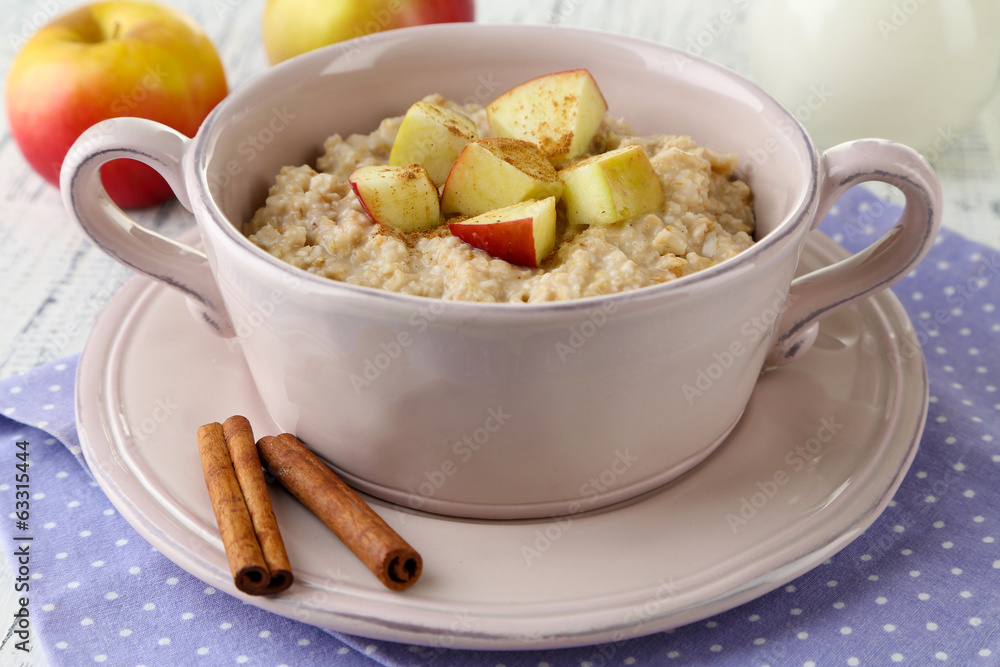 Tasty oatmeal with apples and cinnamon on table close up