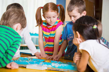 cute preschoolers plaing game on table