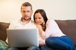 © Nejron Photo - Young cheerful couple with laptop on a sofa in home interior