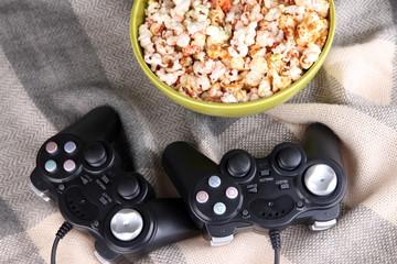 Black game controllers and bowl with pop corn