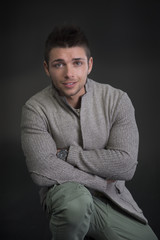 Wall Mural - Attractive young man with sweater, sitting on the floor