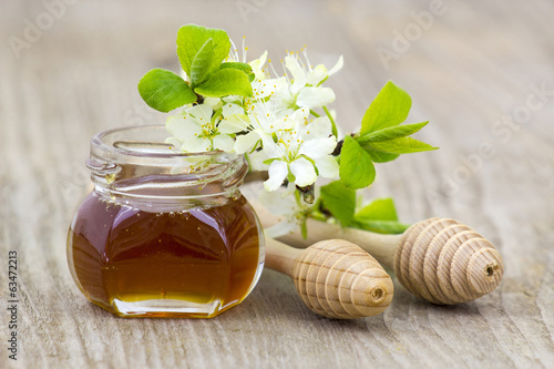 Obraz w ramie Honey in a jar, flowers and honey dippers on wooden background