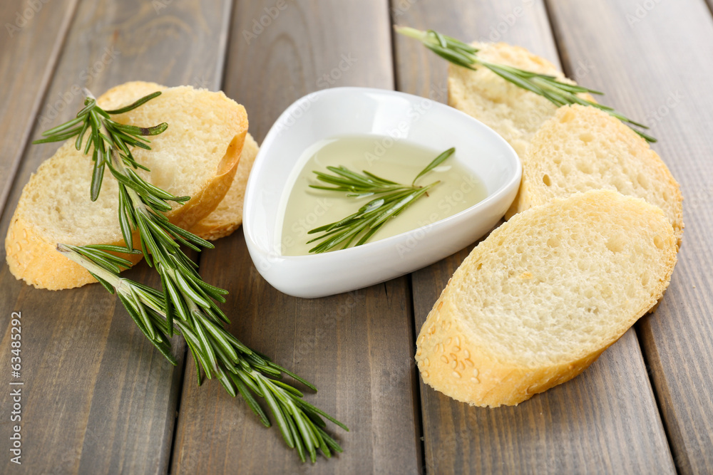 Fresh bread with olive oil and rosemary on wooden table