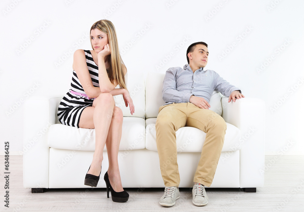 Loving couple sitting on sofa, on light background