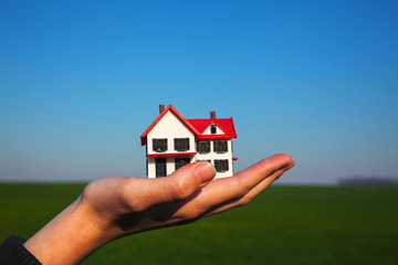 Female hand holding model of residential building