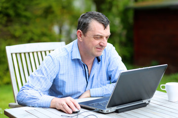 Businessman working from home sitting with laptop in the garden