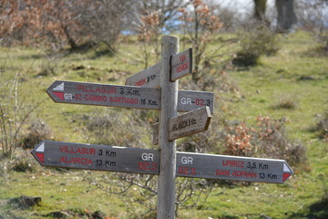 Señal de madera indicadora de direccion y distancia en un cruce