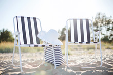 Two Beach Lounges With Beach Bag And White Hat