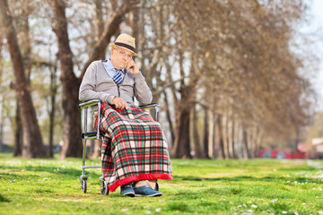 Poster - Grumpy old man sitting in a wheelchair in park