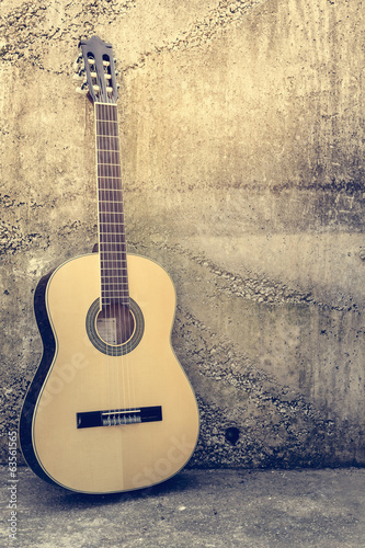 Board z aluminiowym obramowaniem Gitara akustyczna przeciwko grunge teksturowanej ścianie.