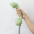 © 2nix - Hand hold vintage telephone green color on white wall background