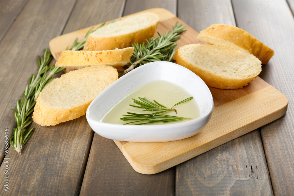 Fresh bread with olive oil and rosemary on wooden table