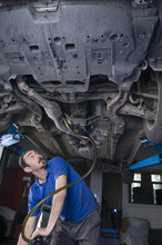 Mechanic Draining Engine Oil At Auto Repair Shop For Oil Change