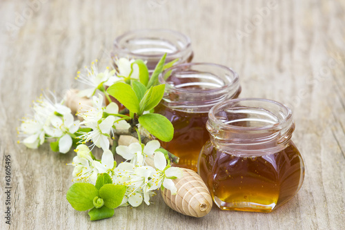 Fototapeta na wymiar Honey, flowers and honey dipper on wooden background