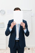 © contrastwerkstatt - geschäftsmann hält ein blatt papier vor sein gesicht