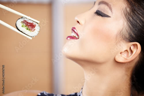 Naklejka samoprzylepna Piękna azjatykcia kobieta je suszi z chopsticks