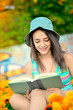 Beautiful young woman with green hat reading a book