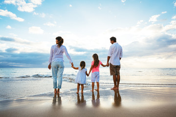 happy young family watching the sunset at the beach