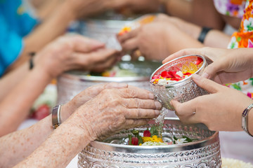 Pour water on the hands of revered elders and gives blessing in