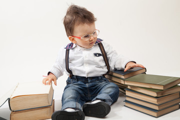 Cute baby boy with eyeglasses looking at a book