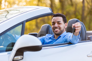 Young black latin american driver holding car keys driving his n