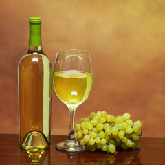 Wine Bottle and Glass of White Wine with Fresh Grapes over beige