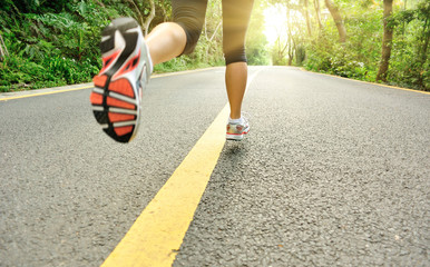 Wall Mural - Runner athlete feet running on road. 