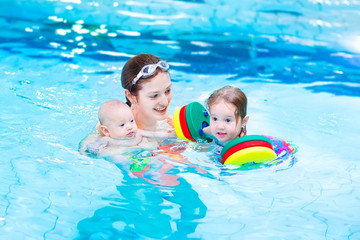 Wall Mural - Young active mother swimming with toddler daughter and baby son