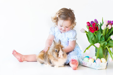 Wall Mural - Cute toddler girl with a bunny on Easter next basket with eggs