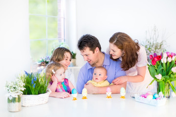 Happy young family with three children having easter breakfast