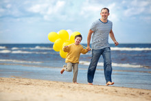 Family With Yellow Balloons Playing On The Beach