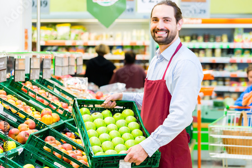 Fotografie, Obraz Supermarkt Angestellter füllt Regale auf