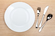 © karandaev - Empty white plate with silverware on wooden table