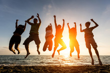 Multiracial Group Of People Jumping At Beach, Backlight