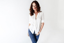Fashion Model In A Blouse And Jeans Barefoot On A White Backgrou