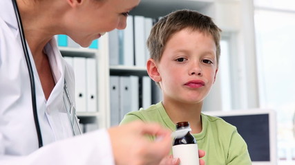 Wall Mural - Doctor giving little boy a spoon of medicine