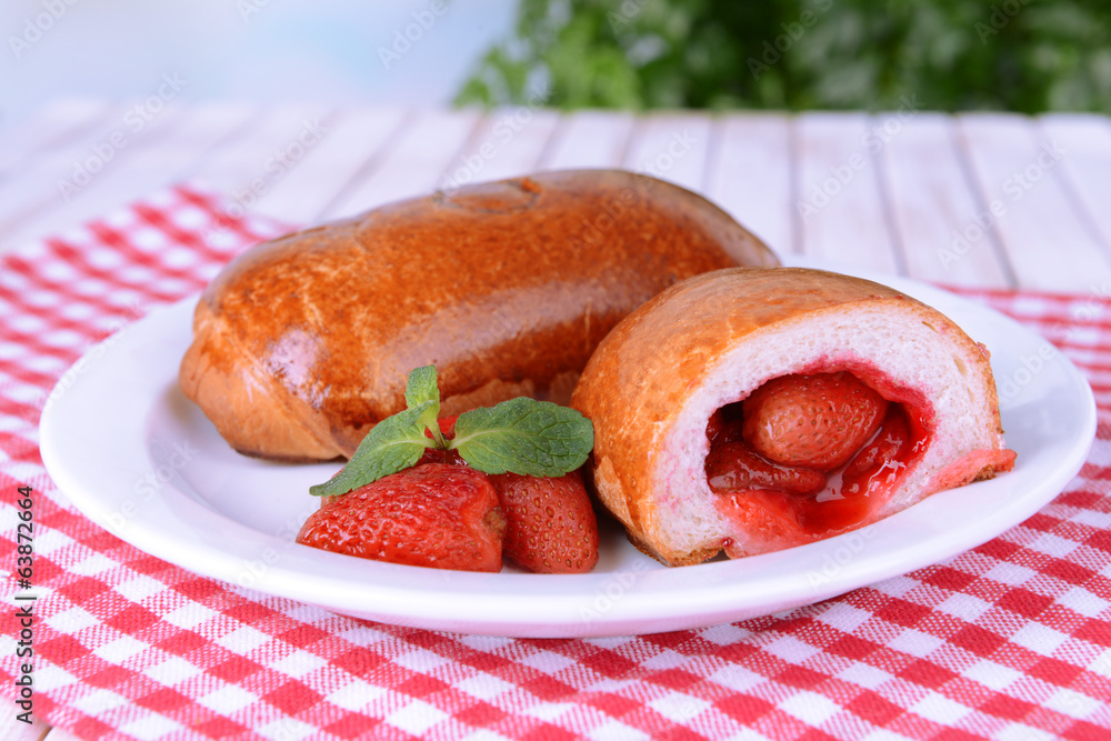Fresh baked pasties with strawberries on plate on table