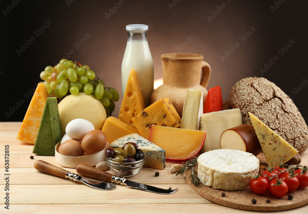 Tasty dairy products on wooden table, on dark background